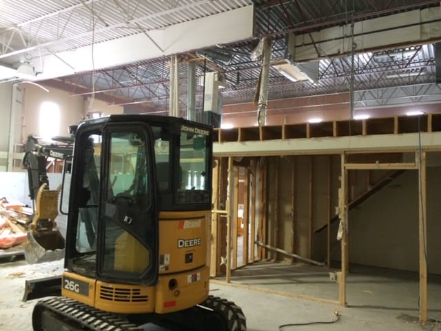 Selective structural removal inside a commercial building in Calgary using a compact excavator to dismantle framing and walls.
